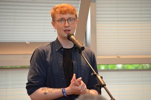 Ein junger Mann mit Brille spricht in ein Mikro